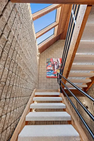 Solid wood beamed staircase with a vaulted ceiling and skylights that bring in warm natural light.