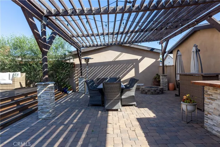 On the lower level are system pavers, a built-in firepit, a large pergola for shade, stacked stone BBQ area.