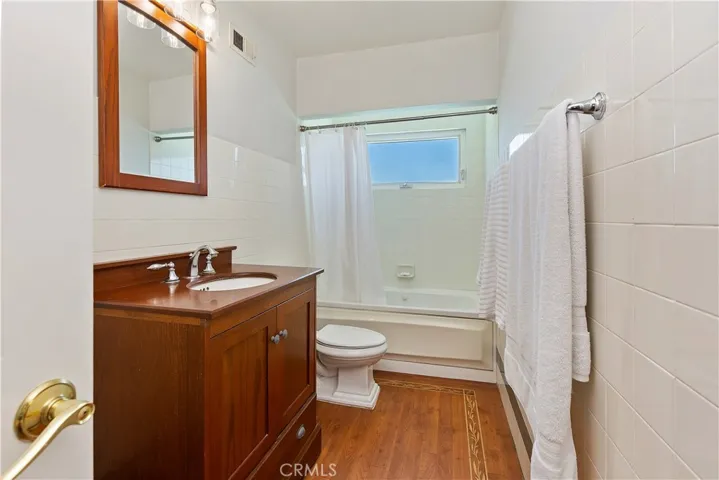 The centerpiece of the bathroom is a spacious tub/shower combination, surrounded by sleek tile walls that exude contemporary charm.