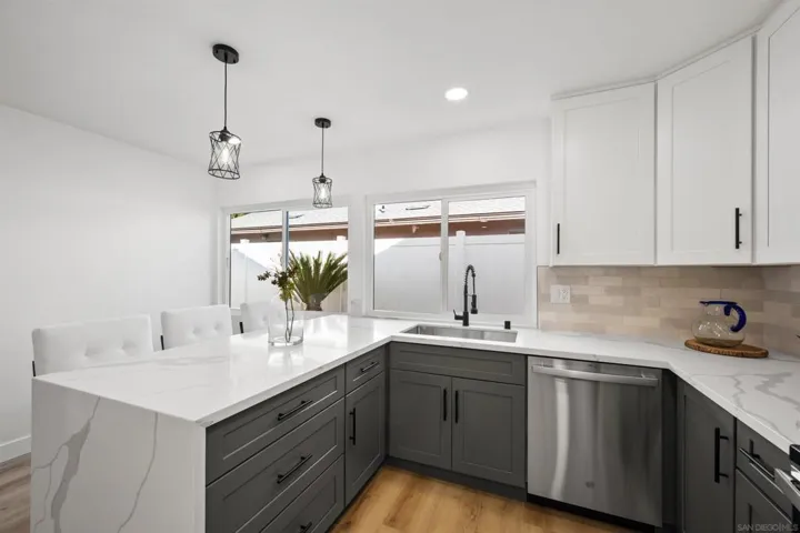 Two toned cabinets encased by quarts countertops and a stainless steal appliance package.