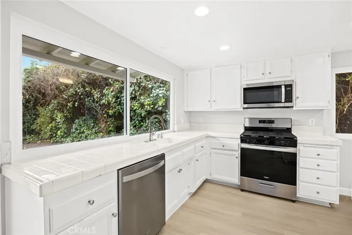 Kitchen offers stainless steal appliances, LED recessed lights and view of the backyard