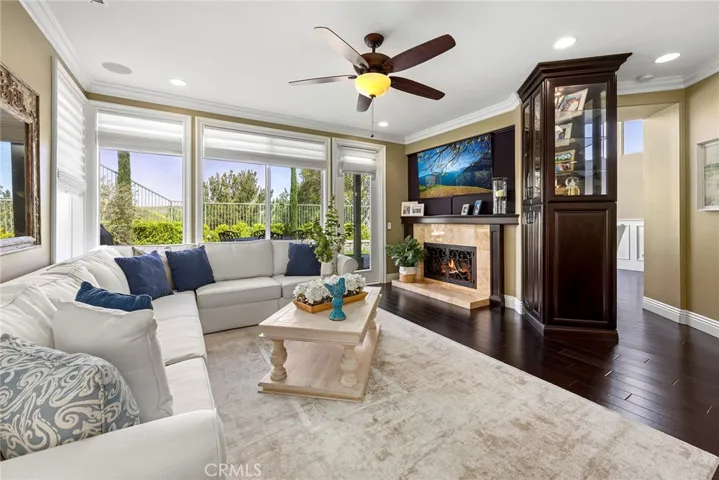 Light and Bright with large open windows to enjoy the outside views. Fireplace has a built-in mantle with wrought iron enclosure, and attached built-in custom glass cabinets. Room is finished off with crown molding & built-in speakers.