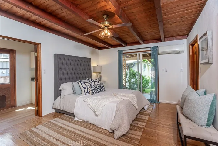Primary suite with warm hardwood flooring, exposed beam ceilings, huge walk in closet!