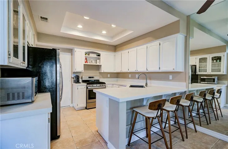 Open kitchen with bright white cabinets, quarts counters, recessed lighting, upgraded appliances & counter bar.
