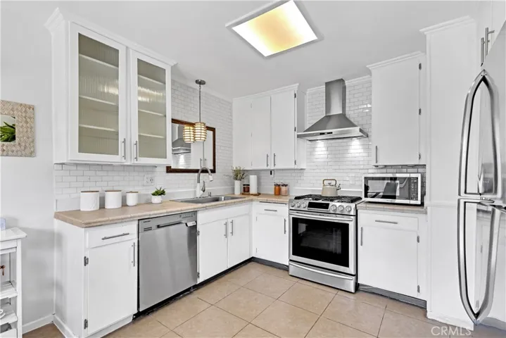 Updated Kitchen with designer backsplash, Stainless steel appliances, tile countertops, and refrigerator included.