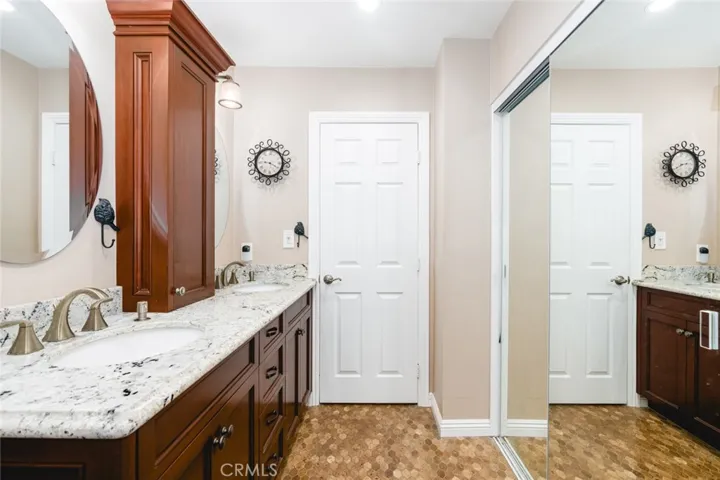 Remodeled primary ensuite bathroom with custom dual sink vanity with granite counter tops