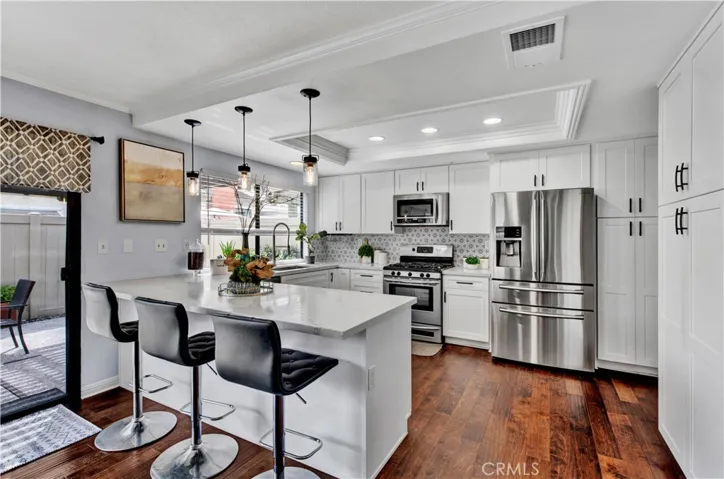 Remolded Sunlit Kitchen that includes Quartz Countertops, Chic Retro Tile Backsplash, Stainless Appliances, Breakfast Bar with Pendent Lighting, Deep Chef's Stainless Sink, and custom White Shaker Self-Closing Cabinetry!