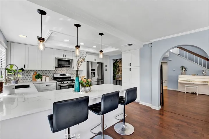 Remolded Sunlit Kitchen that includes Quartz Countertops, Chic Retro Tile Backsplash, Stainless Appliances, Breakfast Bar with Pendent Lighting, Deep Chef's Stainless Sink, and custom White Shaker Self-Closing Cabinetry!