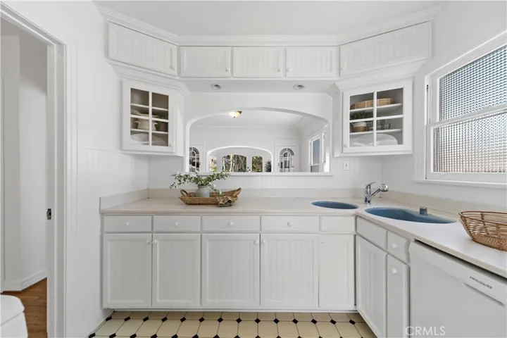 Kitchen offers glass-fronted cabinets, two sinks and a dishwasher.