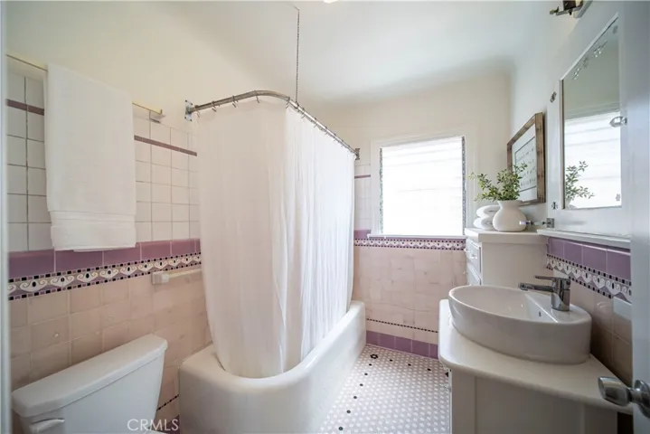 Vintage bathroom with lovely tile work, cast-iron tub and etched glass on the medicine cabinet.