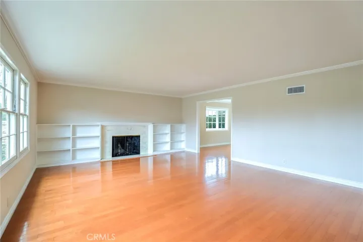 Beautiful living room with hardwood floors, stunning marble fireplace, built in bookcases, crown molding and lot's of natural light,