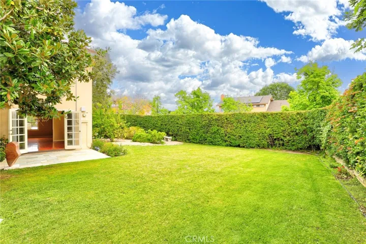 Large grassy area with block wall and lush gardens!