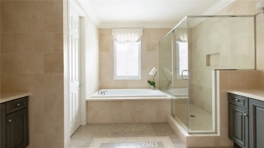 Luxurious ensuite bathroom featuring separate sinks, a jetted tub, and a standing shower.