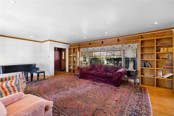 Spacious living room with a spanning bevelled window overlooking the front yard and surrounded by built-in bookcases.