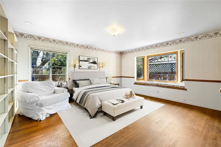 Spacious bedroom with hardwood flooring, built-in bookcases, windows overlooking the backyard, and a large closet with custom built closet organizers.