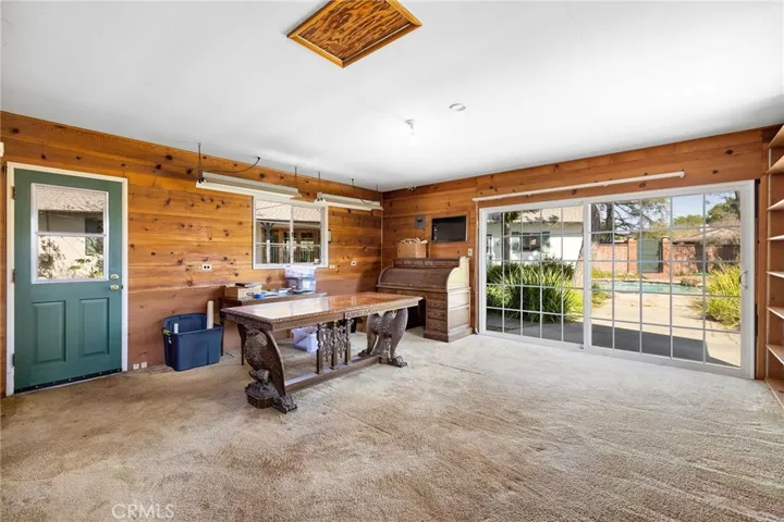 Interior offers carpeted floors, wood paneling walls, and a spanning sliding door that looks into the backyard.