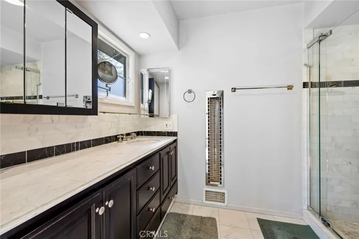 Remodeled bathroom with a custom tiled shower and frameless glass enclosure door.