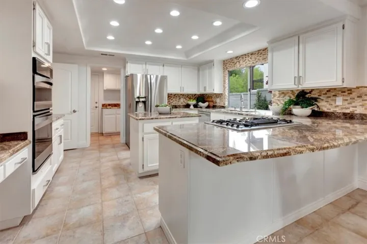 . The grand kitchen features stainless steel appliances, granite countertops, a center island, a breakfast bar, & a breakfast nook.