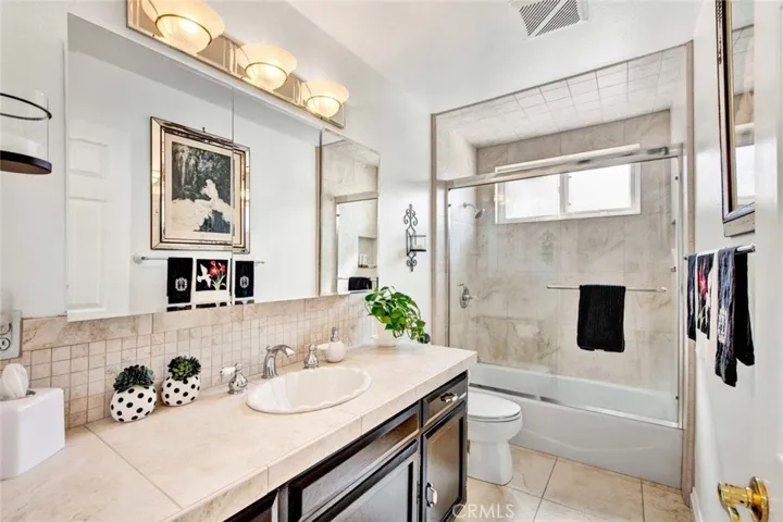 Guest Hall Bathroom With Tile Counters and Tub Shower Combination