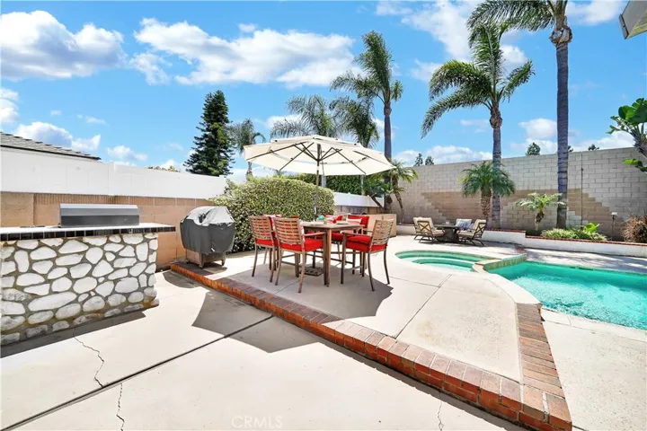 Enjoy outdoor living at its finest with a built-in BBQ, raised planters with palm trees, and a high privacy/sound wall surrounding the sparkling pool and spa.