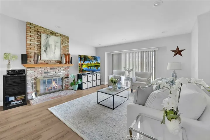 The heart of the home is the inviting living space, featuring a cozy brick fireplace with a wood mantle and raised hearth, perfect for gatherings with loved ones.