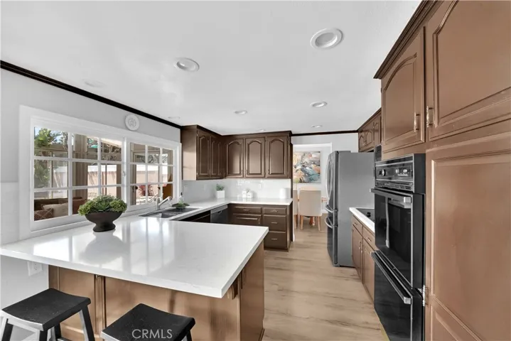 gourmet kitchen, equipped with quartz counters, double ovens, microwave, flat surface cooktop, dishwasher, and recessed lights