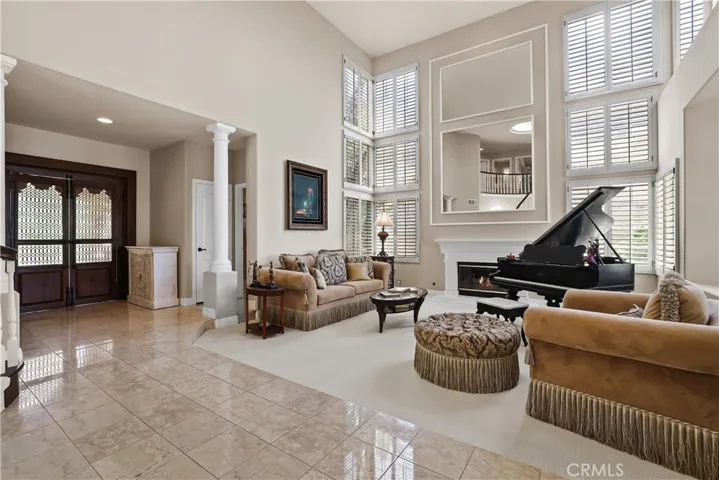 One of a kind Front Doors provide a peaceful entry to a marble flooring to view the two-story high ceilings with windows offering natural lighting and the mirrored wall adorns the expansive fireplace for all to enjoy