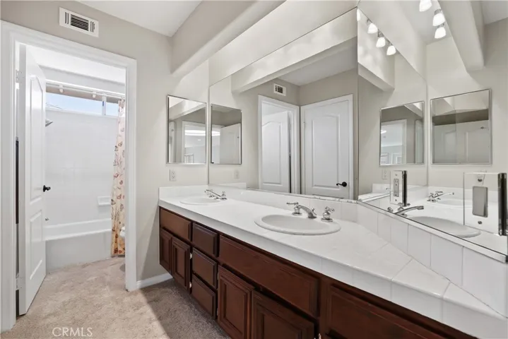 Upstairs Hall bathroom offers dual sinks and private shower/tub water closet