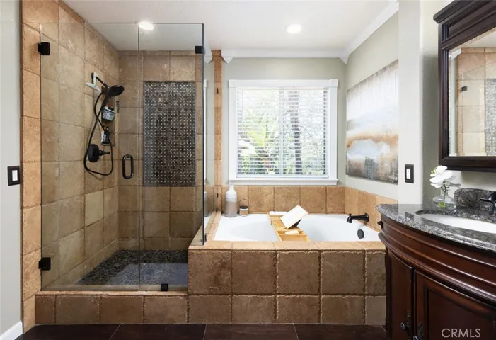 Glass enclosed shower, tumbled stone tile wainscotting and soaking tub in the master bathroom.