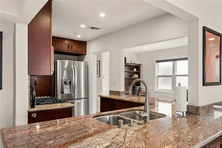 Kitchen with recessed lighting, large granite counter tops and a stainless steel sink.