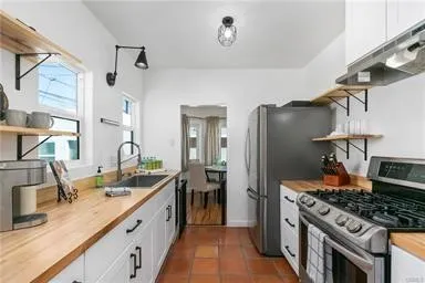 Galley Kitchen with Spanish Pavers, Butcher Block Counters and White Cabinets
