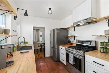 Galley Kitchen with Spanish Pavers, Butcher Block Counters & White Cabinets