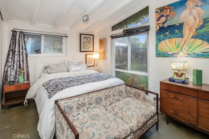 The primary suite has been expanded by incorporating one of the additional 2 bedrooms into its footprint and it is drenched in natural light from an oversized picture windows and is enriched with pitched wood beamed ceilings, ceiling fan, mirrored wardrobe doors, a huge retreat with French doors that lead to the backyard.