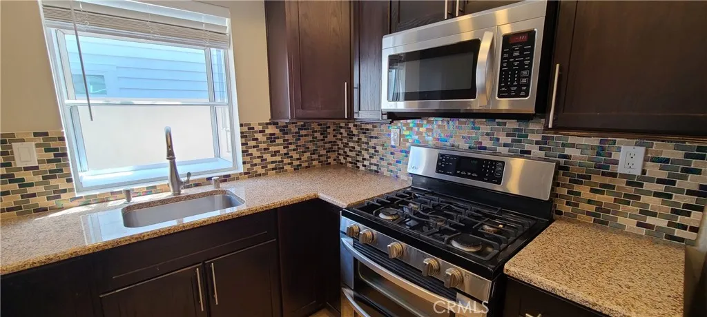 Kitchen with stainless steel appliances, decorated in calming earth tones and beautiful back splash tile accent.