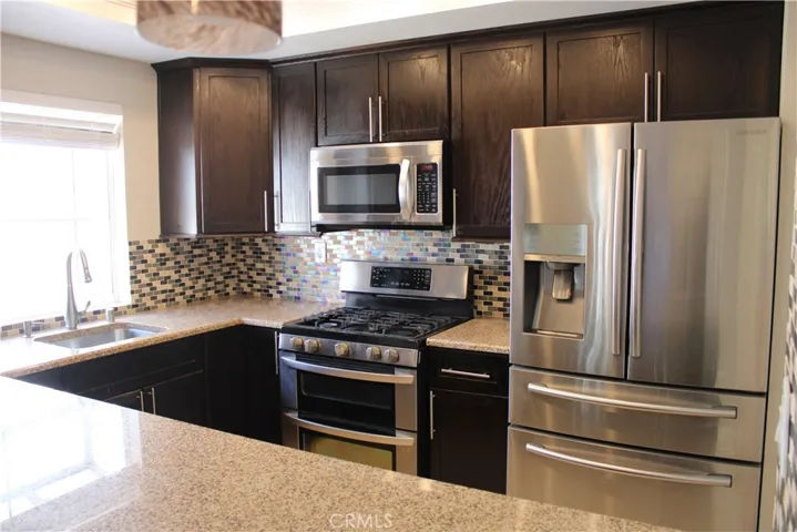 Kitchen with stainless steel appliances, decorated in calming earth tones and beautiful back splash tile.