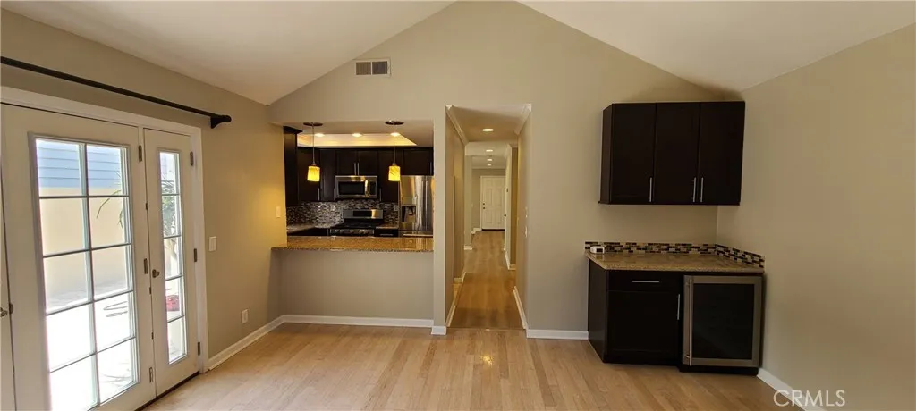 Family room with bar/wine fridge and fireplace, adjacent to the kitchen and side yard/lower patio area.