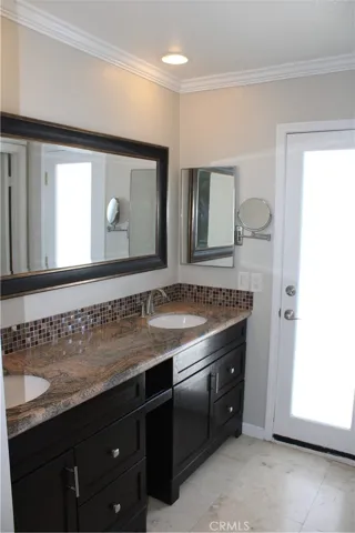 Primary bathroom with dual sinks and access door to spiral staircase leading to upper view deck.