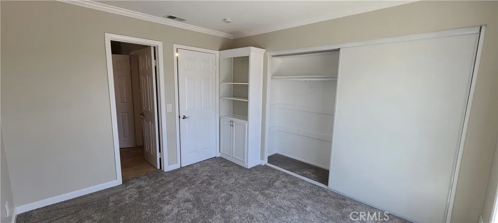 Second bedroom with built-in cabinetry, entry to full bath and sliding door access to front balcony.