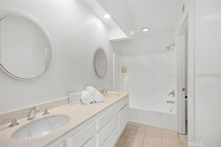 Primary bathroom with dual sinks and shower/tub combo