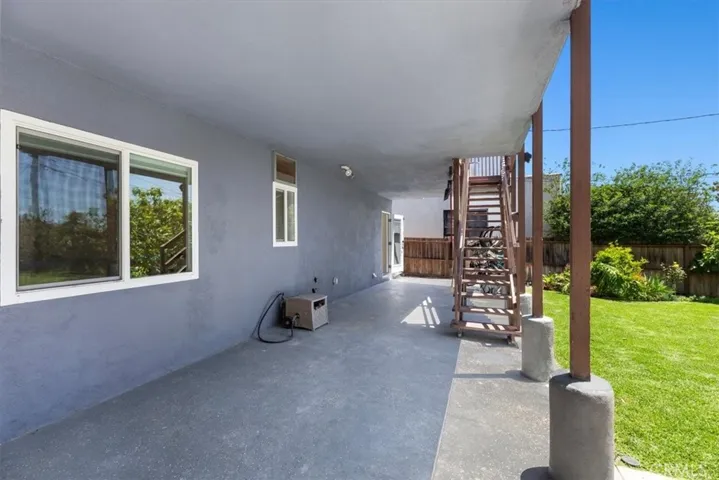 covered patio with stairs leading up to deck off kitchen