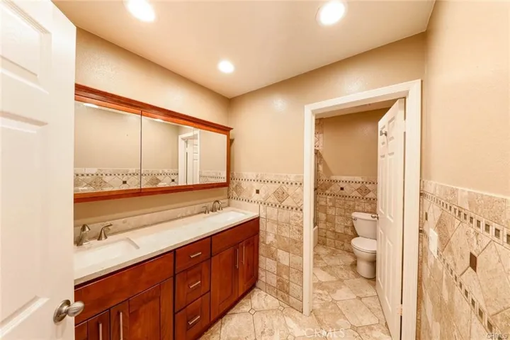 Shared full bath with separate toilet and dual vanities