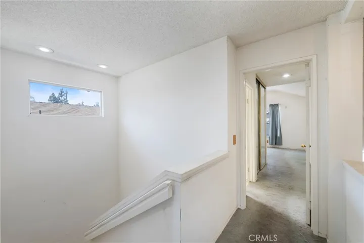 Hallway at the top of the stairs with views of the stairwell and primary suite!