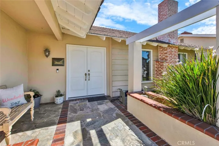 Welcoming Covered Front Porch, double Door Entry, Brick-Accented Hardscape, Tropical Landscaping