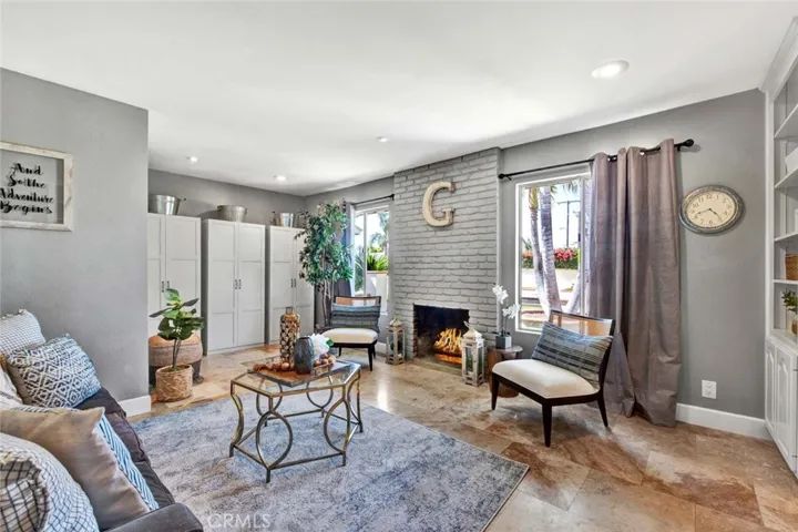 Formal Living Room with Fireplace, Travertine Flooring, and Custom Built-In Shelving
