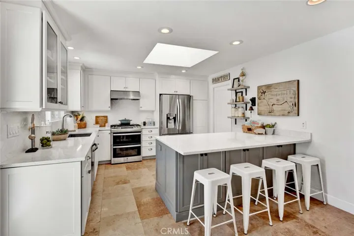 Beautiful Chef's Kitchen with Quartz Counters, Skylight, Recessed Lighting, Breakfast Bar, Stainless Appliances, Walk-In Pantry, Custom White Shaker Self-Closeing Cabintry with Under Cabinet Lighting, Pull-Outs, Hidden Trash, and Glass Display Panels