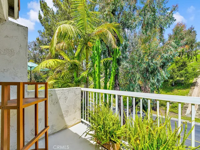 The balcony off of the primary bedroom has a gorgeous view of a lush hillside.