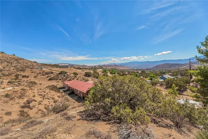 View from top of property showing Back of Home with two separate fenced areas directly behind home. and steel building across to otherside of property