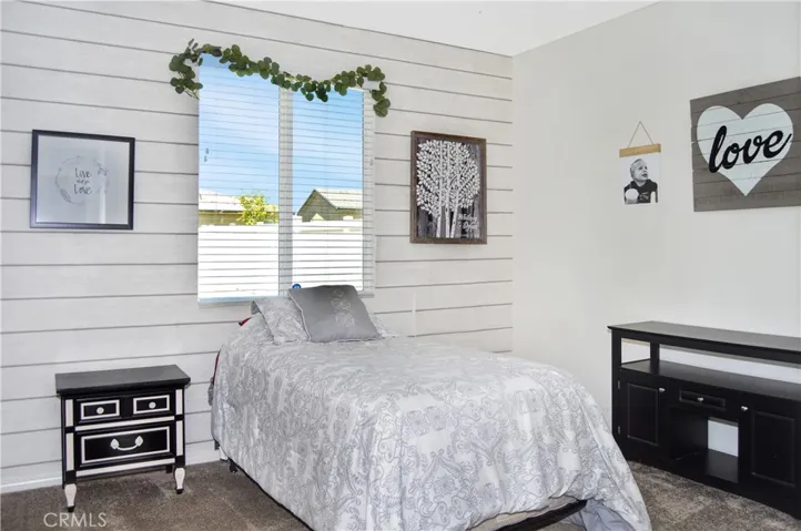 The main floor 5th bedroom offers views of the backyard, a ceiling fan, and easy access to the full bathroom next door.