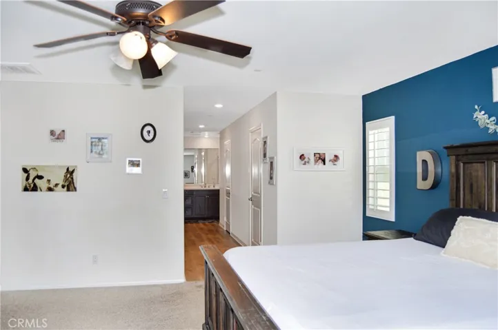 The oversized main bedroom suite sits at the end of the hall upstairs for a little extra privacy and features upgraded plush carpeting, louvered shutters, a ceiling fan, dual walk-in closets, and an en suite bath. There's plenty of room for a retreat area, too.