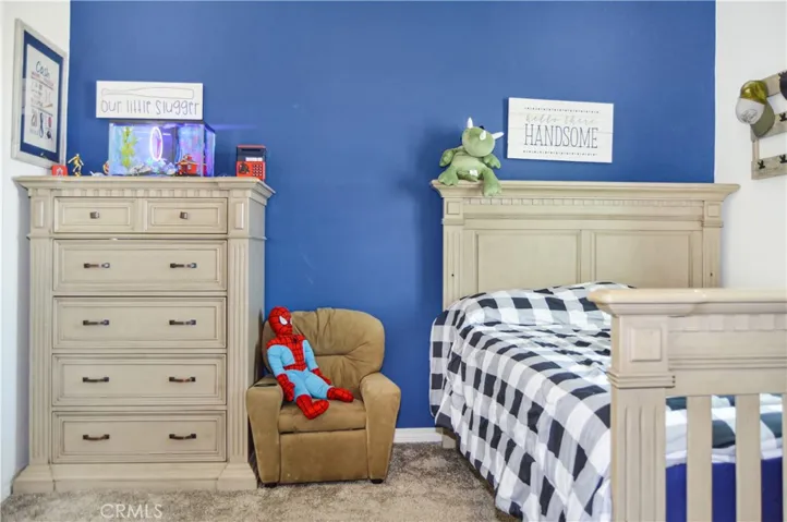 The 2nd bedroom upstairs is down the hall from the main suite and features a walk-in closet, ceiling fan, window blinds, and fun blue accent wall